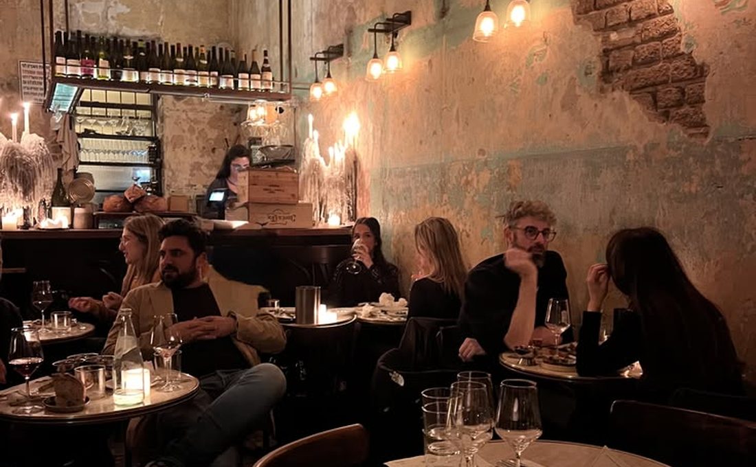 Une salle de bistrot complète en soirée, tables occupées et lumière chaude